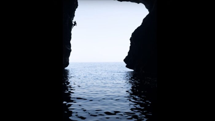 climber in silhouette with ocean below